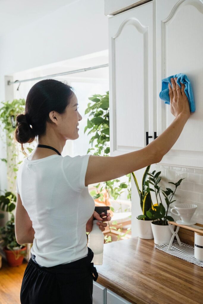 A lady wiping clean a cabinet