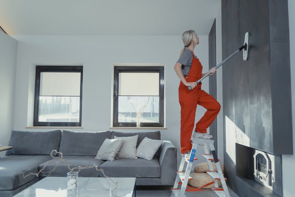 A lady on a ladder cleaning a wall with a mop